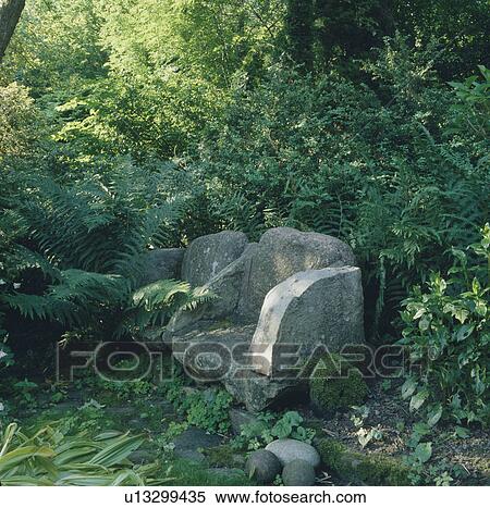 Stock Photography - Rustic stone chair in country garden. Fotosearch