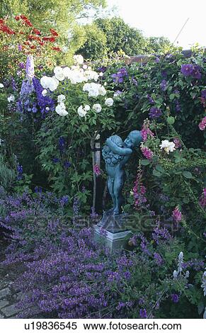 Stock Photography - Sculpture in scented flowering borders in country garden in summer. Fotosearch