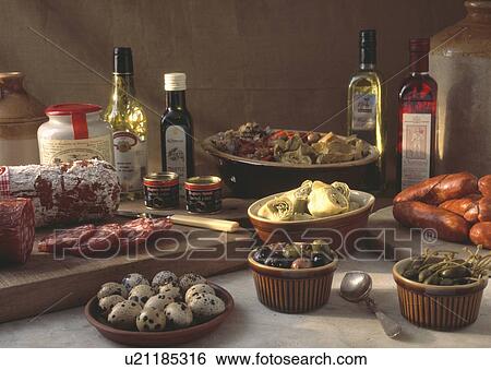 Stock Photograph - Selection of starters including quails eggs and saucisson with bottles of olive oil and vinegar . Fotosearch