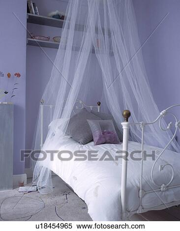 Sheer White Voile Curtains Above White Wrought Iron Bed With White Linen In Mauve Bedroom Stock Photography