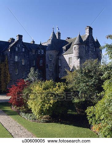 Stock Photography - Shrubs on lawn in front of large castellated house in Scotland. Fotosearch
