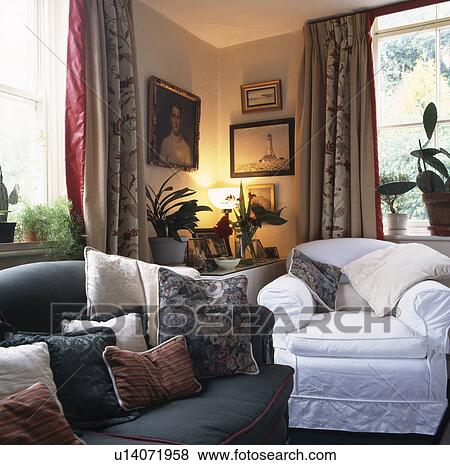 Sofa and white armchair in livingroom with lighted lamp on table in the corner of the room View Large Photo Image Stock Photo - Sofa and white armchair in livingroom with lighted lamp on table in the corner of the room. Fotosearch