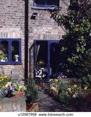 Stock Photo - Spring plants in pots on patio of small cottage. Fotosearch