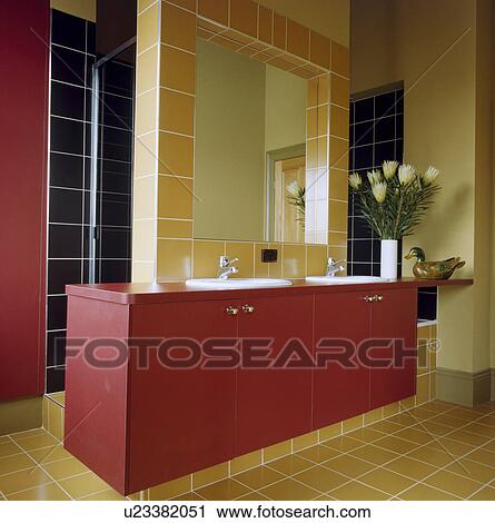 Square mirror inset in yellow tiled border above double basins in red vanity unit in modern bathroom with yellow tiled floor View Large Photo Image Stock Image - Square mirror inset in yellow tiled border above double basins in red vanity unit in modern bathroom with yellow tiled floor. Fotosearch