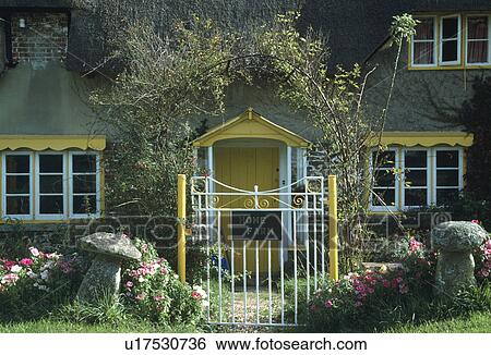 Staddlestones on either side of yellow and white metal gate in front of cottage with yellow gable above windows View Large Photo Image Stock Photograph - Staddlestones on either side of yellow and white metal gate in front of cottage with yellow gable above windows. Fotosearch