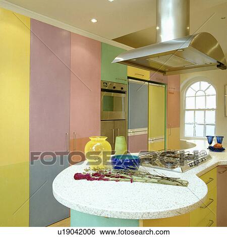 Stainless steel extractor above hob in marble-topped peninsular unit in multi-coloured pastel kitchen View Large Photo Image Stock Photograph - Stainless steel extractor above hob in marble-topped peninsular unit in multi-coloured pastel kitchen . Fotosearch