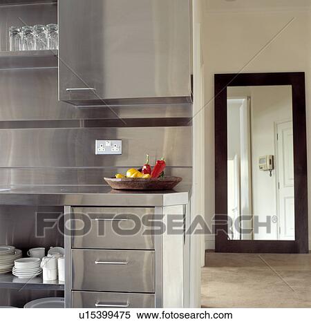 Stainless steel fitted cupboards and splashback in modern kitchen with view through doorway of large mirror View Large Photo Image Stock Photography - Stainless steel fitted cupboards and splashback in modern kitchen with view through doorway of large mirror. Fotosearch