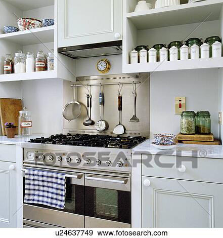 Stainless steel range oven in pale grey kitchen with marble worktops below storage jars on shelves View Large Photo Image Stock Photo - Stainless steel range oven in pale grey kitchen with marble worktops below storage jars on shelves. Fotosearch