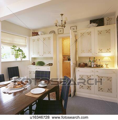 Stock Photo - Stencilled panels on cupboards in white country dining room. Fotosearch