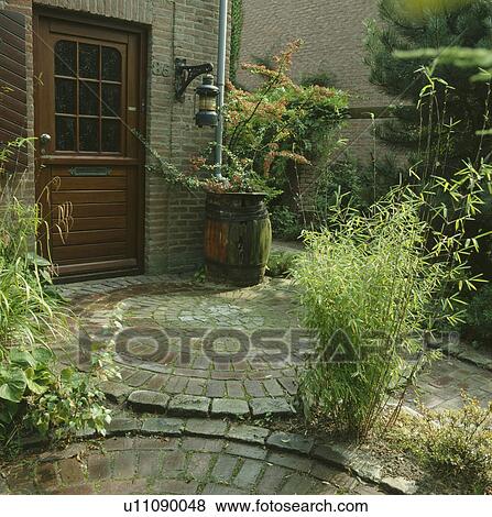 Stock Photo - Stone paving in green town garden in summer. Fotosearch