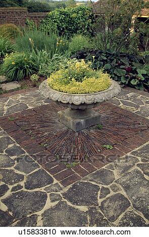 Stone urn in the centre of stone and brick paving in country garden in summer View Large Photo Image Stock Image - Stone urn in the centre of stone and brick paving in country garden in summer. Fotosearch