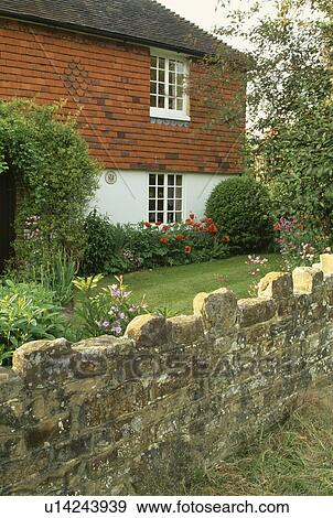 Stone Wall In Front Of Country Cottage Garden Stock Photo Stone Wall In Front Of Country Cottage Garden Stock Photo