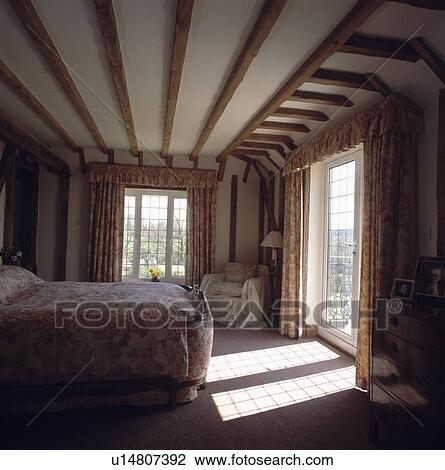 Sunlight streaming through window in beamed country bedroom with Toile de Jouy bedlinen View Large Photo Image Stock Image - Sunlight streaming through window in beamed country bedroom with Toile de Jouy bedlinen. Fotosearch