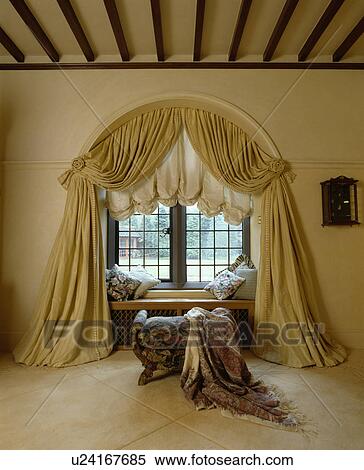 Stock Photography - Swagged curtains and ruched blind on arched window. Fotosearch