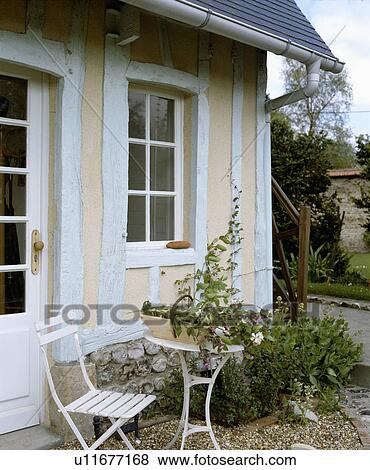 Table and chairs in front of traditional white and cream timbered country cottage in France View Large Photo Image Stock Photo - Table and chairs in front of traditional white and cream timbered country cottage in France. Fotosearch