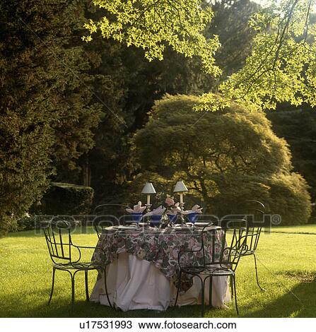 Stock Image - Table and chairs on lawn in country garden in summer. Fotosearch