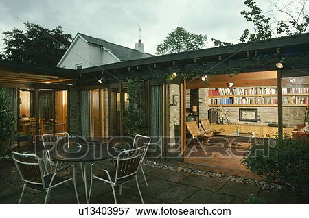 Table and chairs on patio in front of seventies single storey house with glass doors and view of living room View Large Photo Image Stock Photo - Table and chairs on patio in front of seventies single storey house with glass doors and view of living room. Fotosearch