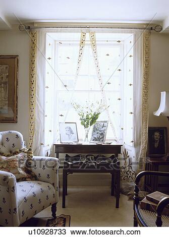 Table in front of window with white voile curtains in traditional living room View Large Photo Image Stock Image - Table in front of window with white voile curtains in traditional living room. Fotosearch