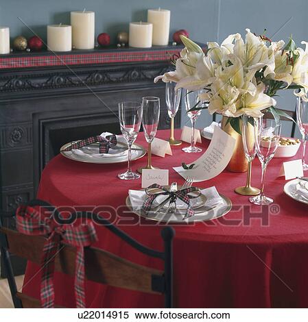 Table laid for Christmas dinner with white crockery on red tablecloth and floral arrangement of white lilies View Large Photo Image Stock Photography - Table laid for Christmas dinner with white crockery on red tablecloth and floral arrangement of white lilies. Fotosearch