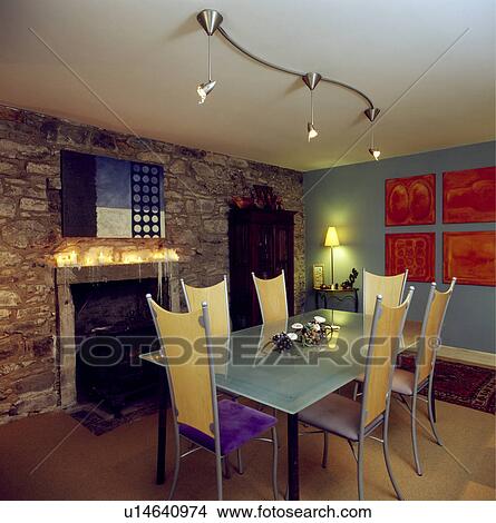 tall-backed chairs and rectangular table below halogen spotlights in dining room with fireplace in stone wall View Large Photo Image Picture - tall-backed chairs and rectangular table below halogen spotlights in dining room with fireplace in stone wall. Fotosearch