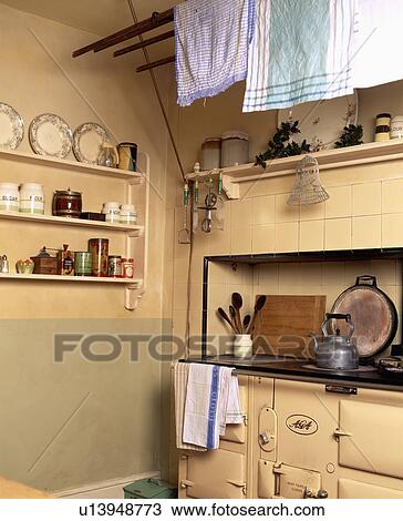 Teacloths drying on rack above cream Aga in traditional kitchen with crockery on small shelving unit View Large Photo Image Stock Image - Teacloths drying on rack above cream Aga in traditional kitchen with crockery on small shelving unit. Fotosearch