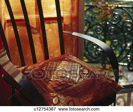 Terracotta and gold sari fabric cushion on wooden chair View Large Photo Image Stock Photo - Terracotta and gold sari fabric cushion on wooden chair. Fotosearch