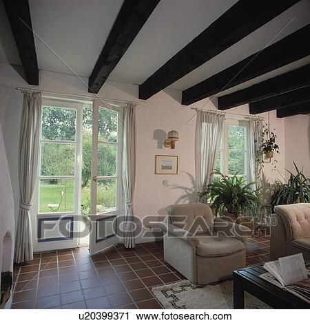Tiled floor in white living room with French doors and beamed ceiling View Large Photo Image Stock Image - Tiled floor in white living room with French doors and beamed ceiling. Fotosearch