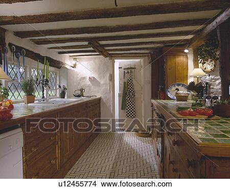 Picture - Tiled worktop in beamed kitchen with herringbone patterned white tiled flooring. Fotosearch
