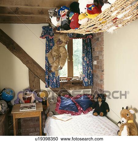 Toys displayed in rope hammock above child's bed in cottage bedroom  View Large Photo Image Stock Image - Toys displayed in rope hammock above child's bed in cottage bedroom . Fotosearch