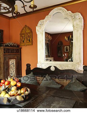 Picture - Traditional bedroom with large white carved mirror and terracotta painted walls.. Fotosearch