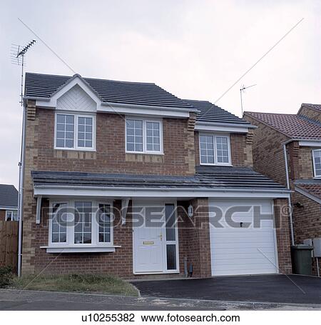 Stock Image - Traditional newbuild brick house with integral garage on small estate. Fotosearch