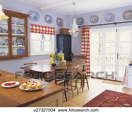 Traditional simple cottage kitchen with wooden table and chairs and red checked curtains. View Large Photo Image Picture - Traditional simple cottage kitchen with wooden table and chairs and red checked curtains.. Fotosearch