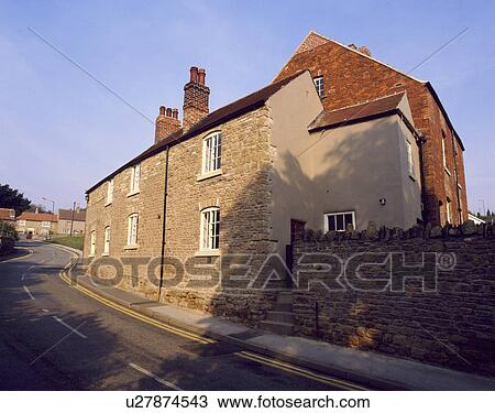 Stock Image - Traditional stone cottage beside the road in country village. Fotosearch