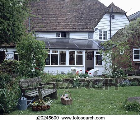 Stock Image - Traditional white clapboard house with conservatory extension. Fotosearch
