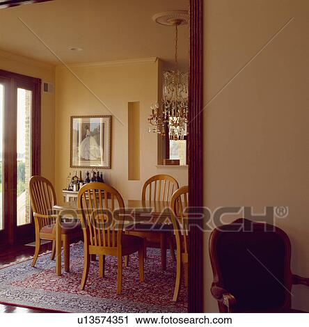 Stock Image - Traditional wooden table and chairs on patterned carpet in modern diningroom. Fotosearch