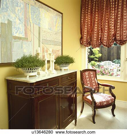Traditional yellow living room with antique marble-topped cupboard and patterned red blind View Large Photo Image Stock Image - Traditional yellow living room with antique marble-topped cupboard and patterned red blind. Fotosearch