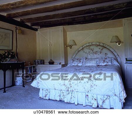 Upholstered bed with matching quilt and vallance in beamed country bedroom View Large Photo Image Stock Image - Upholstered bed with matching quilt and vallance in beamed country bedroom. Fotosearch