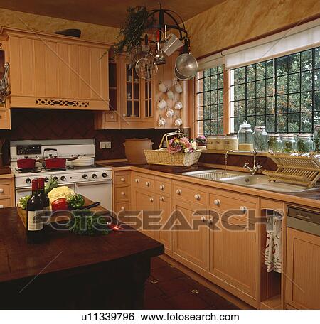 Vegetables on table in peach kitchen with paint effect marbling on wall and graining on wooden cupboard doors View Large Photo Image Stock Photograph - Vegetables on table in peach kitchen with paint effect marbling on wall and graining on wooden cupboard doors . Fotosearch