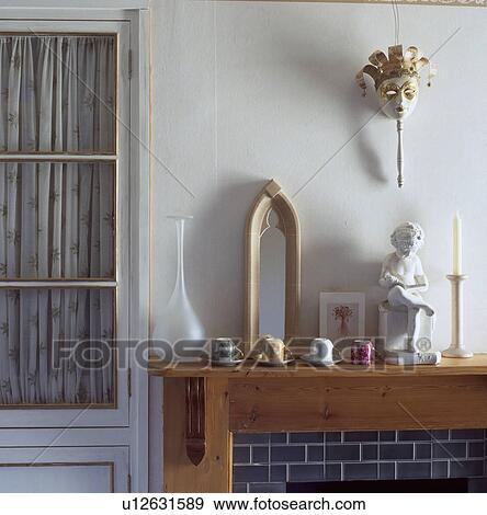 Stock Photo - Venetian mask above collection of miniature cups with mirror and small statue on mantelpiece. Fotosearch