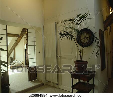 Vertical radiator and houseplant on small table beside door in white hall with sliding opaque glazed doors View Large Photo Image Picture - Vertical radiator and houseplant on small table beside door in white hall with sliding opaque glazed doors. Fotosearch