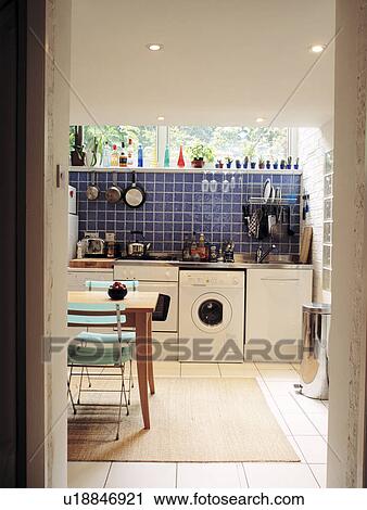 View through doorway of white basement kitchen with blue wall tailes above washing machine and dishwasher View Large Photo Image Stock Image - View through doorway of white basement kitchen with blue wall tailes above washing machine and dishwasher. Fotosearch