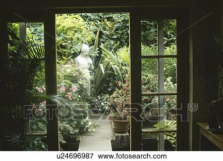 View through French doors to classical statue in small lushly planted town garden View Large Photo Image Stock Photo - View through French doors to classical statue in small lushly planted town garden. Fotosearch