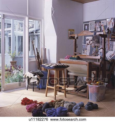 Stock Photograph - Weaving loom set up by open french windows with view onto garden.. Fotosearch