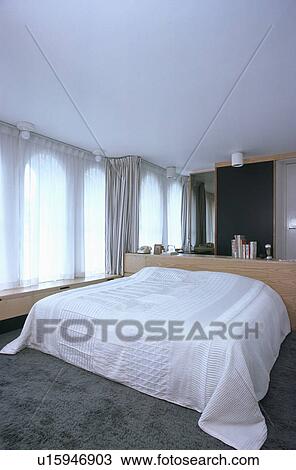 White Bedcover On Bed In White Bedroom With Plush Grey