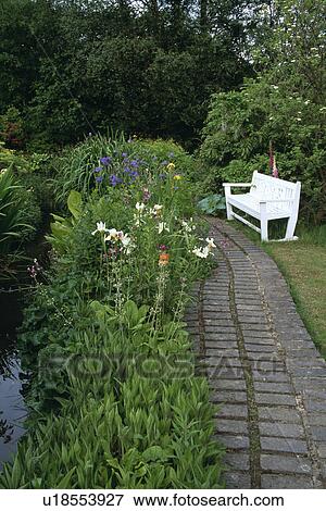 White bench beside paved path and stream in country garden View Large Photo Image Stock Photo - White bench beside paved path and stream in country garden. Fotosearch