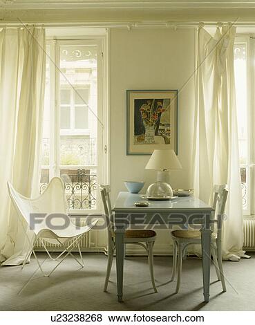 White butterfly chair and white curtains in French dining room with pastel blue table and cane-seated chairs View Large Photo Image Stock Photo - White butterfly chair and white curtains in French dining room with pastel blue table and cane-seated chairs. Fotosearch