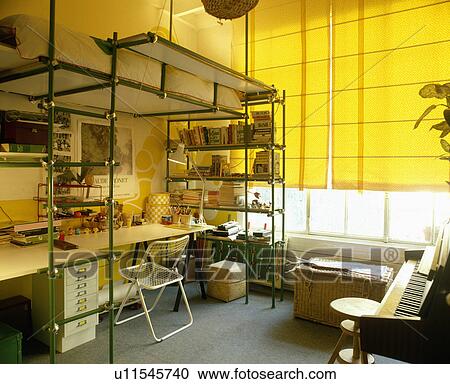 White Desk And Chair Below Platform Bed On Metal Frame With Integral Shelves In Teenage Bedroom Stock Image