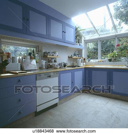 White dishwasher in blue kitchen extension with grey flooring and glass roof above sink View Large Photo Image Stock Photo - White dishwasher in blue kitchen extension with grey flooring and glass roof above sink. Fotosearch