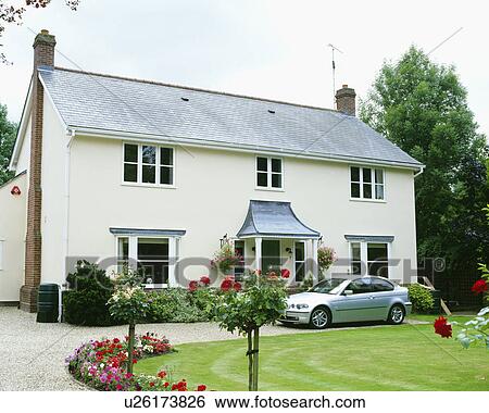 Stock Photograph - White exterior of detached suburban house with drive and lawn and flower beds in front. Fotosearch