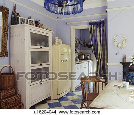 White glass-fronted cupboard and large cream refrigerator in pastel blue kitchen with blue+white chequerboard floor View Large Photo Image Picture - White glass-fronted cupboard and large cream refrigerator in pastel blue kitchen with blue+white chequerboard floor. Fotosearch